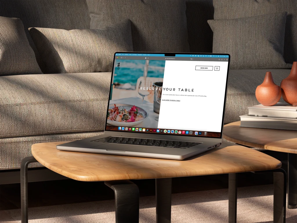 immagine che contiene computer portatile su tavolino di un salotto, dovano sullo sfondo e il computer mostra un sito web per ristoranti